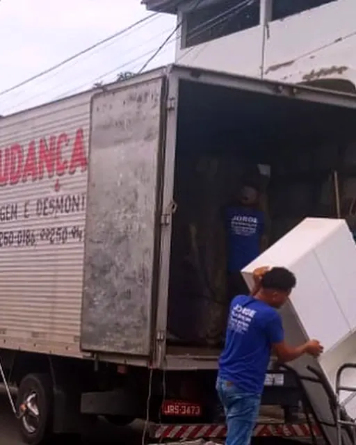 Funcionário levando uma geladeira para o caminhão com carrinho